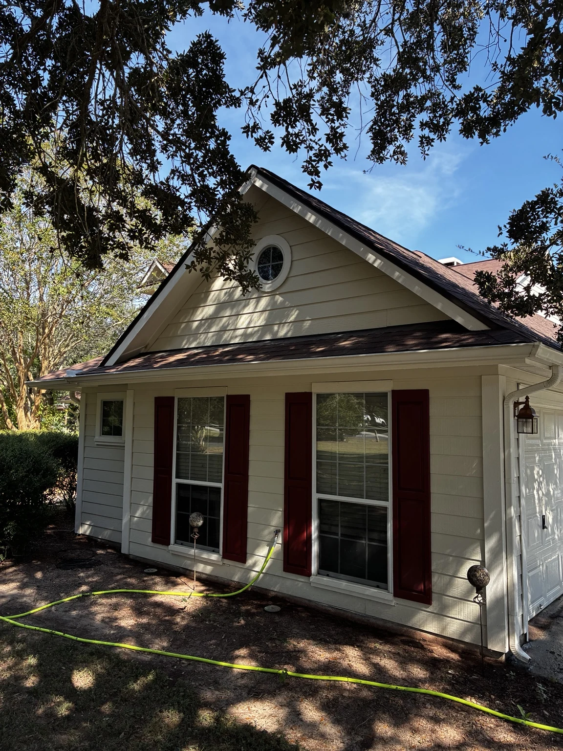 A freshly washed home with white siding and red shutters from a GuddShots job